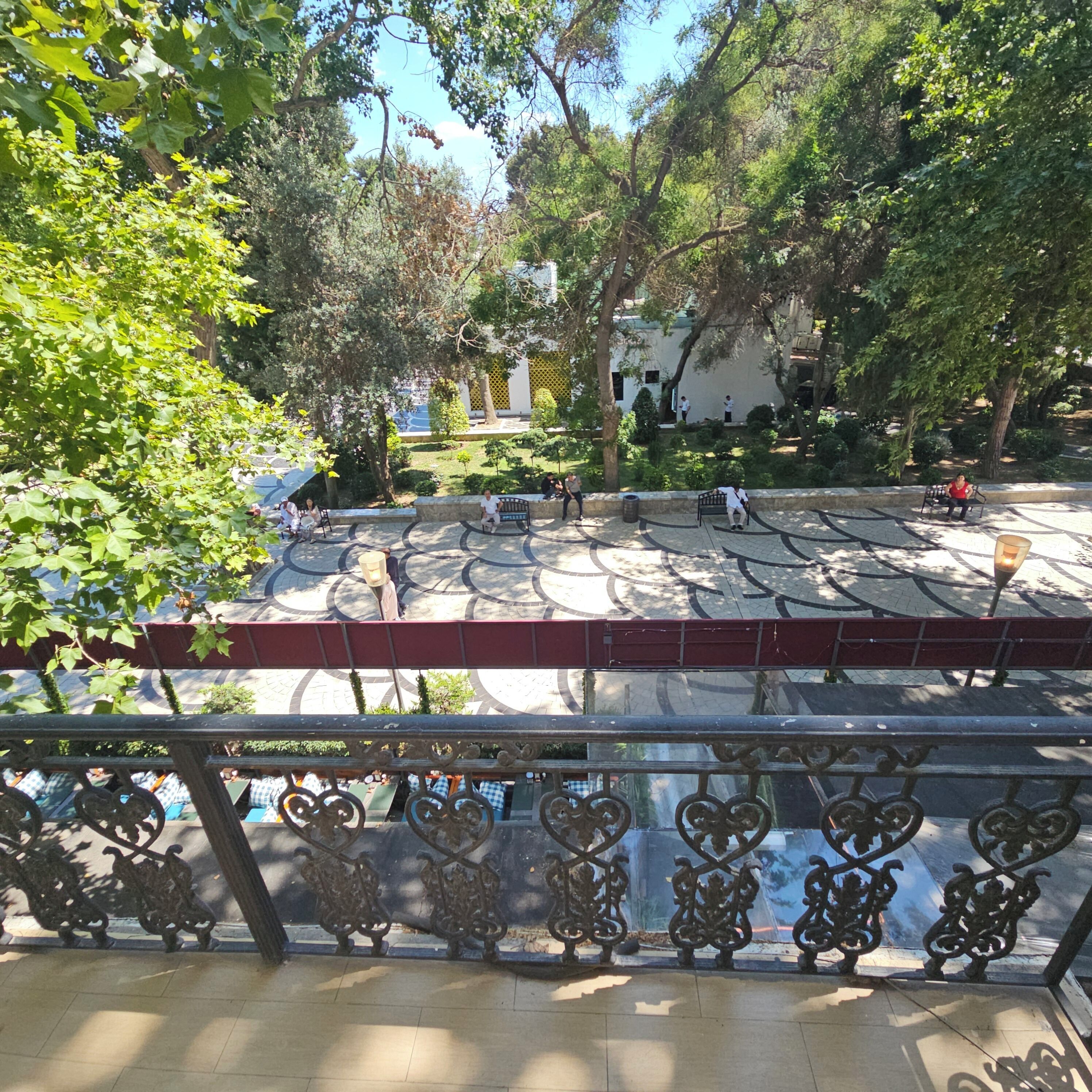 Une cour avec un sol à motifs, des bancs et des arbres.