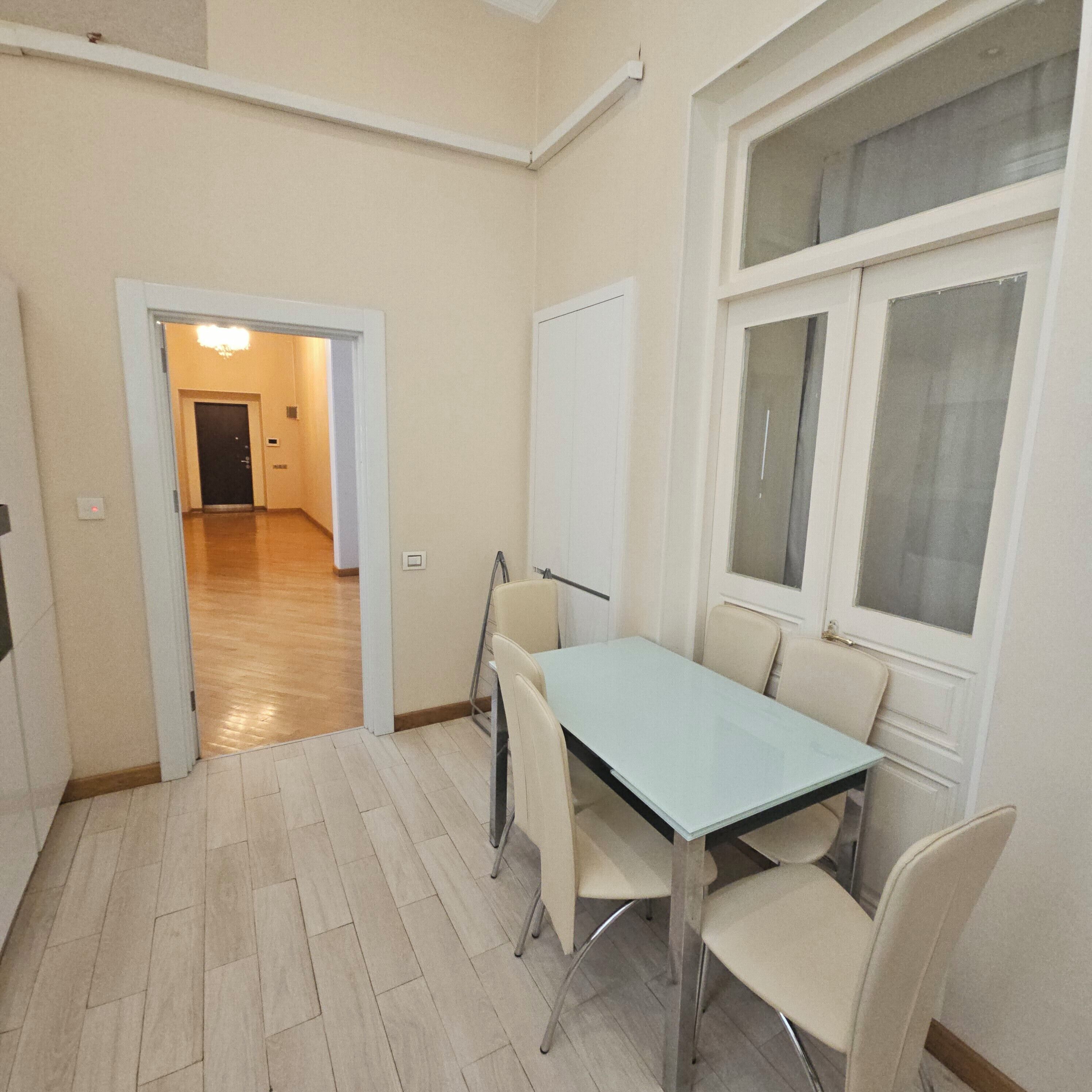 Une pièce comprenant une table à manger, des chaises, un tableau blanc et une fenêtre.