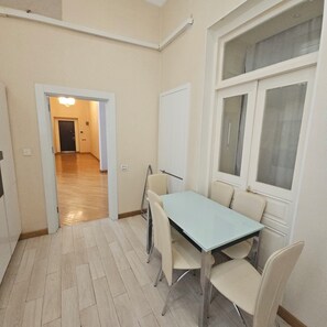 Ein Zimmer mit Esstisch, Stühlen, einer Tafel und einem Fenster.