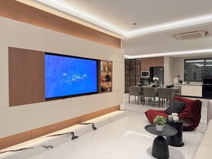 A modern living room with a flat-screen TV, a sofa, a coffee table, and a dining area with chairs and a table. - Tremendous 6-bedroom house with AC in Bang Lamung District (Bang Lamung District)