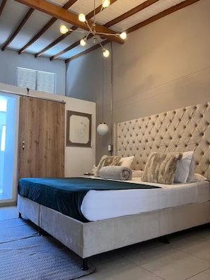 A bedroom with a large bed, a wooden wardrobe, a hanging light fixture, and a framed picture on the wall. - Luxury Provence Terrace (Medellín)