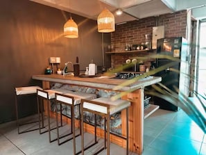 A modern kitchen with a central island, bar stools, hanging lights, and a brick backsplash. - Luxury Provence Terrace (Medellín)