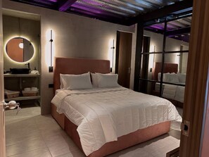 A modern bedroom with a large bed, a bedside table, a round mirror, and a built-in shelf with a sink. - Luxury Penthouse in Provenza (Medellín)
