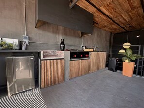 A modern kitchen with a built-in grill, wooden accents, and a potted plant. - Luxury Penthouse in Provenza (Medellín)
