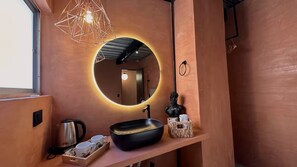 A modern bathroom with a round mirror, a black sink, and a geometric light fixture. - Luxury Penthouse in Provenza (Medellín)