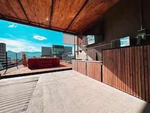 An outdoor terrace with a wooden ceiling, a red sofa, and a view of mountains. - Luxury Penthouse in Provenza (Medellín)