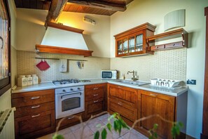 Uma cozinha com armários de madeira, fogão a gás, micro-ondas e pia.