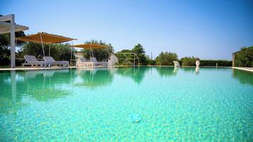 Una piscina cristallina con lettini e ombrelloni, immersa nel verde.