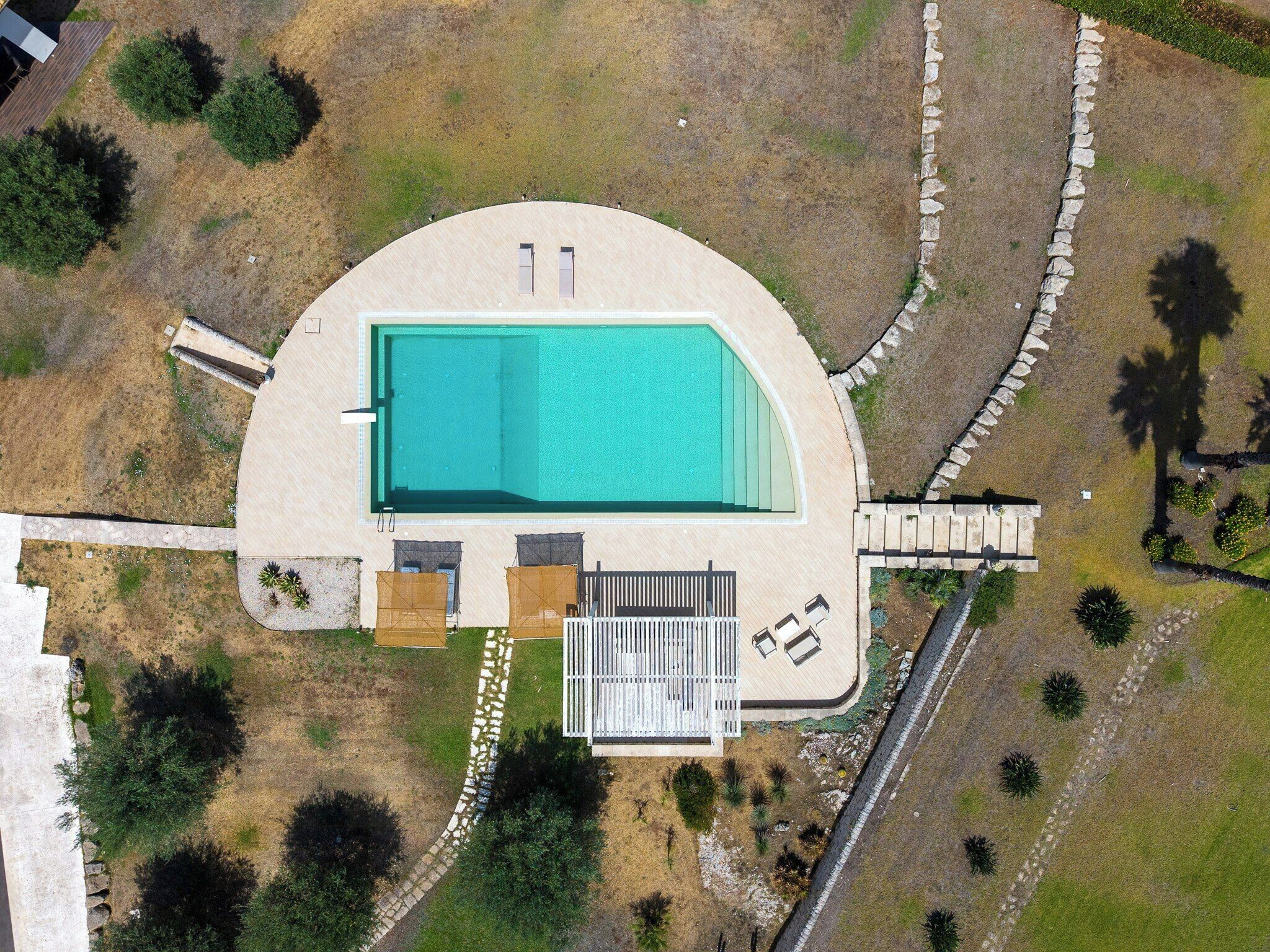 Vue aérienne d’une propriété dotée d’une piscine, d’un patio couvert et d’un jardin aménagé.
