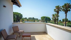 A balcony with two wicker chairs and a small table, overlooking a coastal landscape with trees and a clear sky. - Sicilian villa with pool 400m above sea level (Avola)