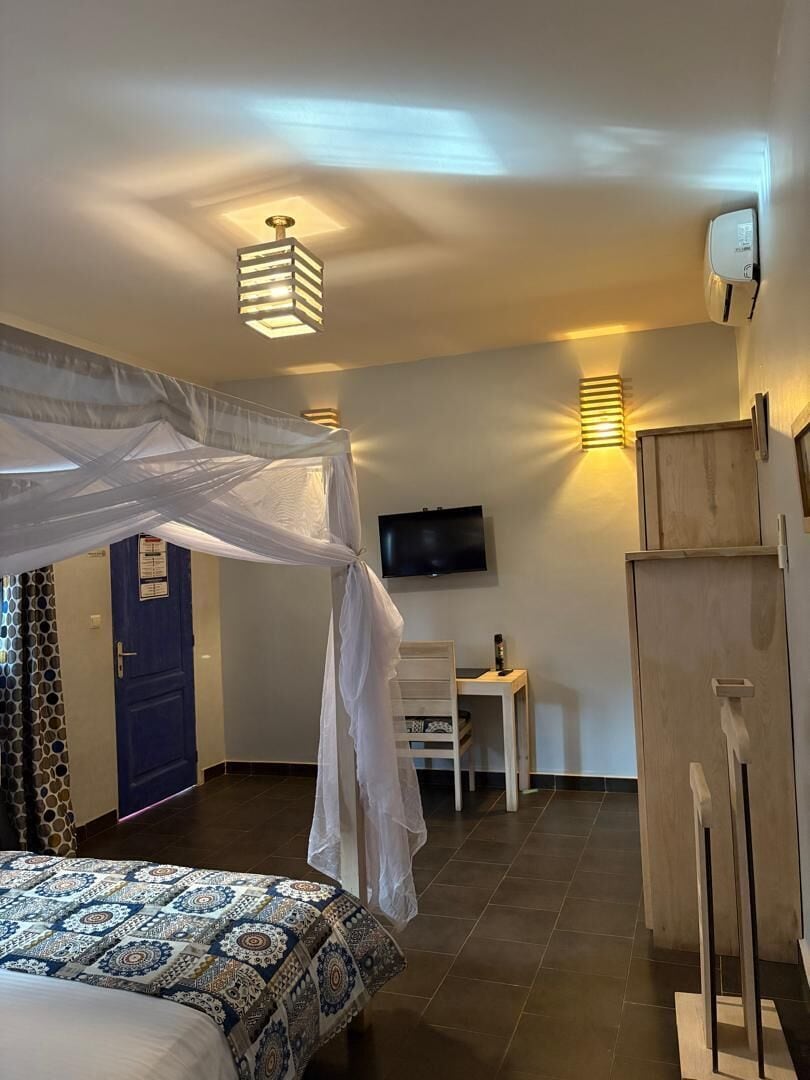 Un dormitorio con cama, escritorio, televisor y armario.