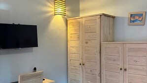 Een kamer met een bureau, een televisie, een kledingkast en een airconditioning.