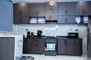 A modern kitchen with dark cabinets, a stove, and a microwave.