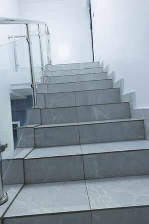 A set of grey marble stairs leading to a glass door entrance.