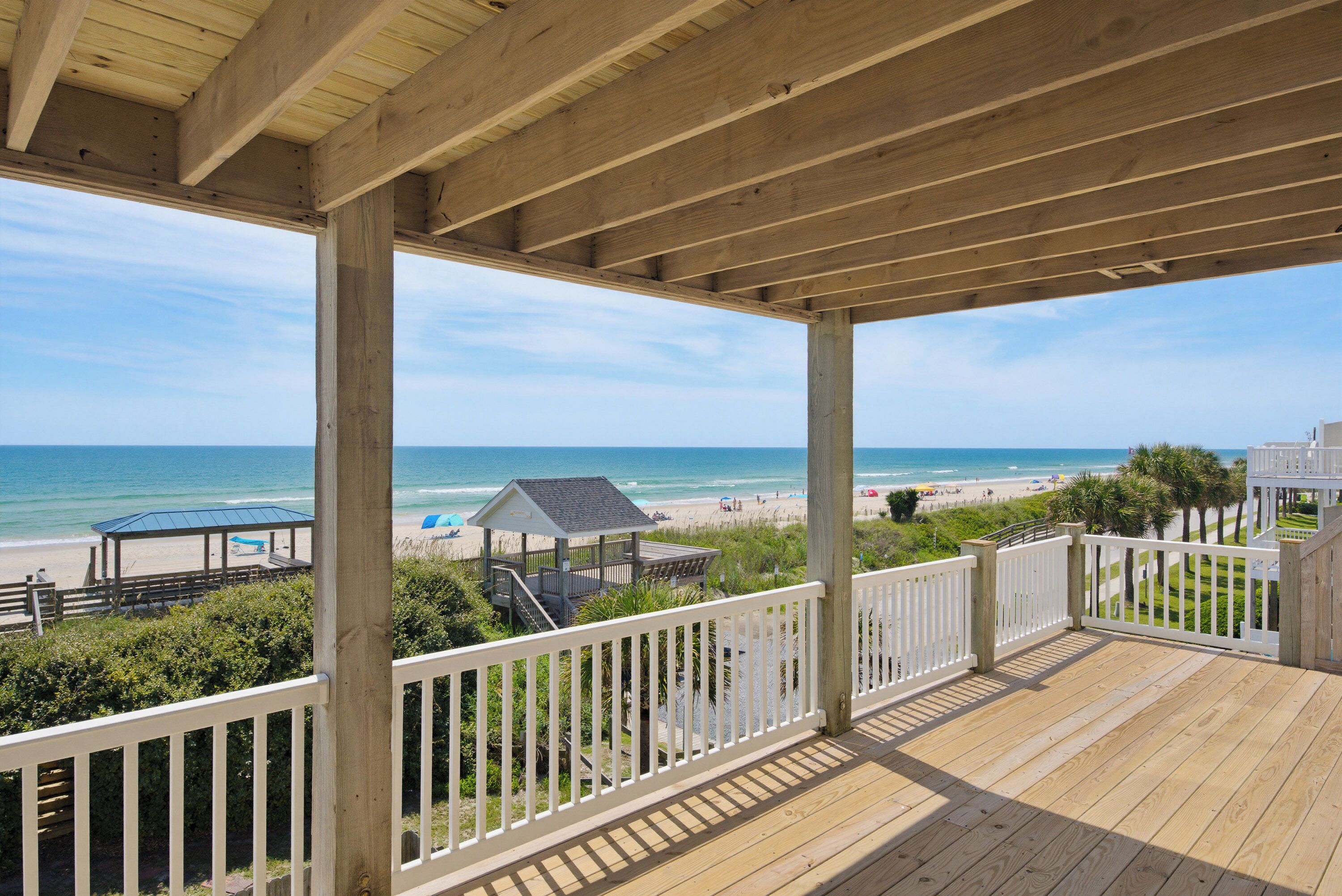 A wooden deck with a view of the beach and ocean.