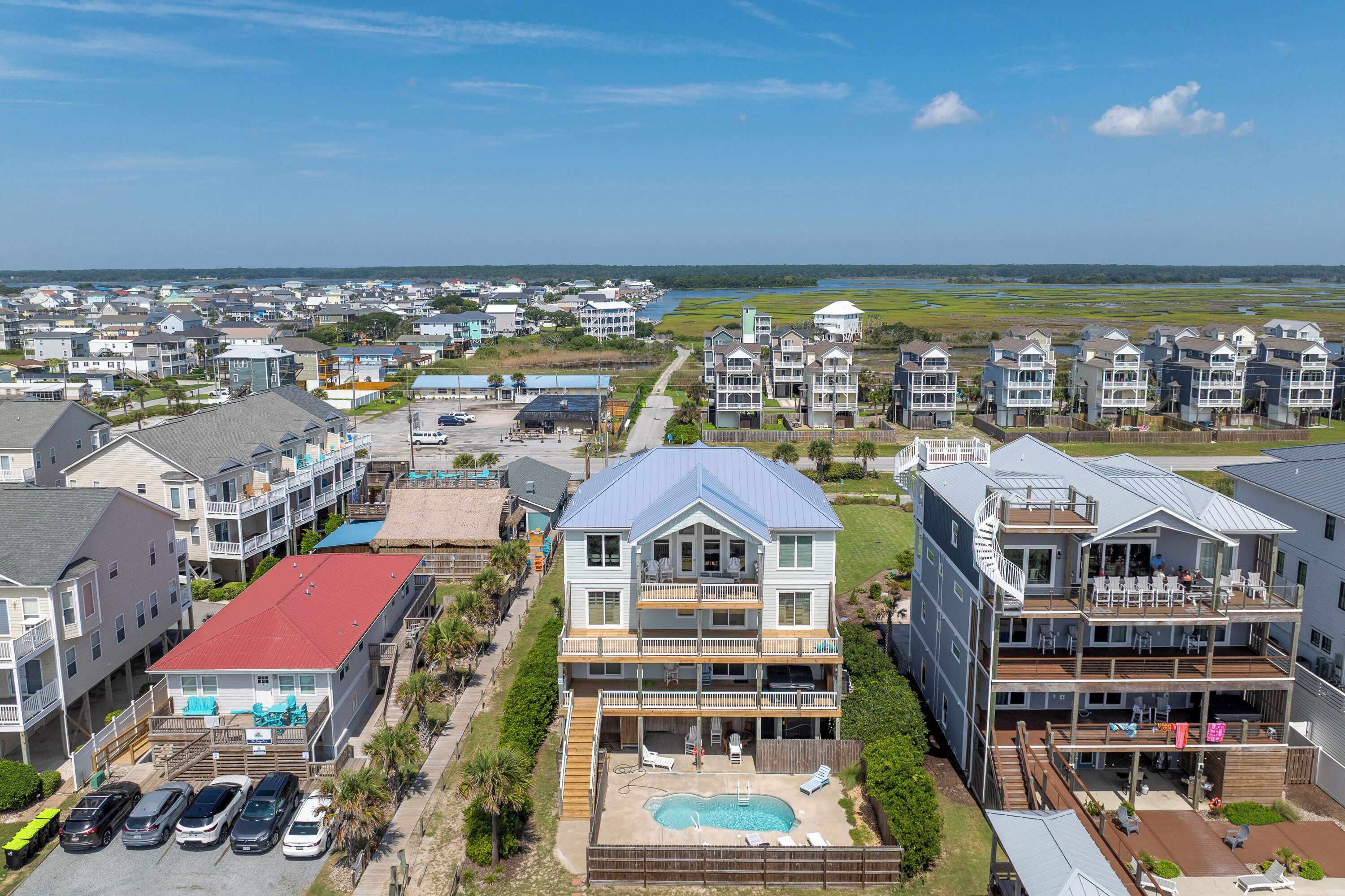 A coastal residential area with multiple two-story houses featuring balconies, a swimming pool, and a view of the ocean.