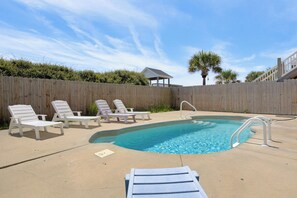 A swimming pool with lounge chairs and a wooden fence. - Oceanfront pool and pirate playhouse (North Topsail Beach)