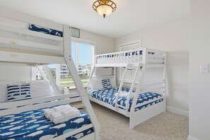 A room with bunk beds, a window with blinds, and a ceiling light fixture. - Oceanfront pool and pirate playhouse (North Topsail Beach)