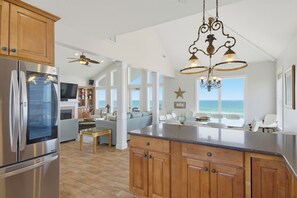 A modern kitchen with a large island, stainless steel appliances, and a view of the ocean. - Oceanfront pool and pirate playhouse (North Topsail Beach)