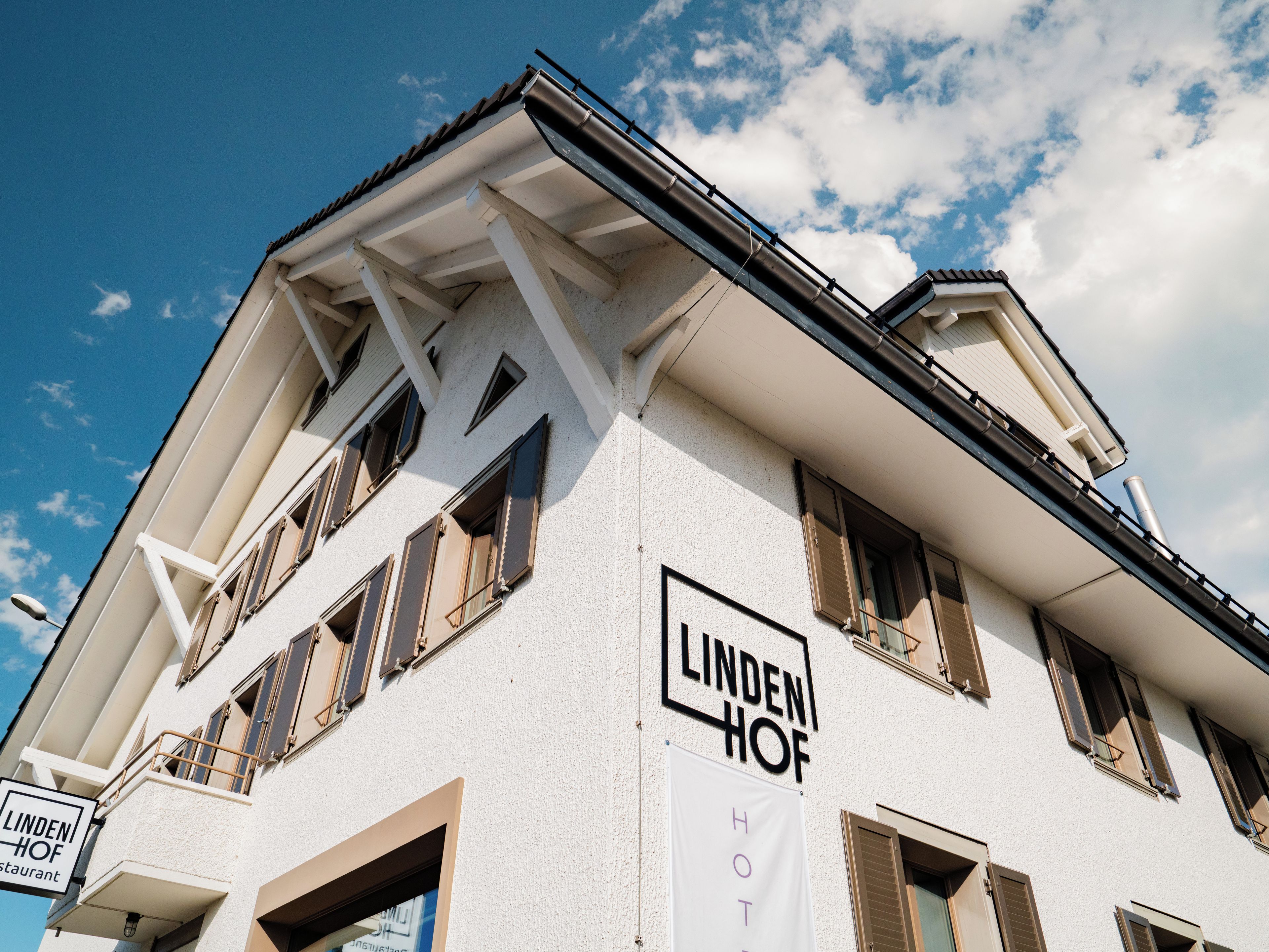 Ett hotell som heter ”Lindenhof” med en vit fasad, flera fönster och en balkong.