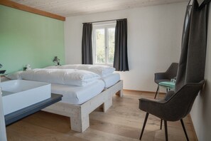 Un dormitorio con cama, una silla, una ventana y un lavamanos.
