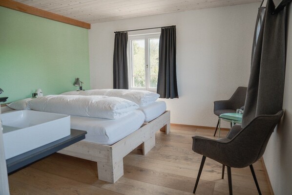 A bedroom with a bed, a chair, a window, and a sink.