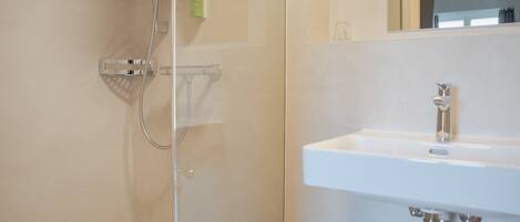 A bathroom with a shower, a sink, and a mirror.