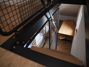 A staircase with a metal railing leading to a room with a wooden table and a chair. - Hotel Lindenhof (Entlebuch)