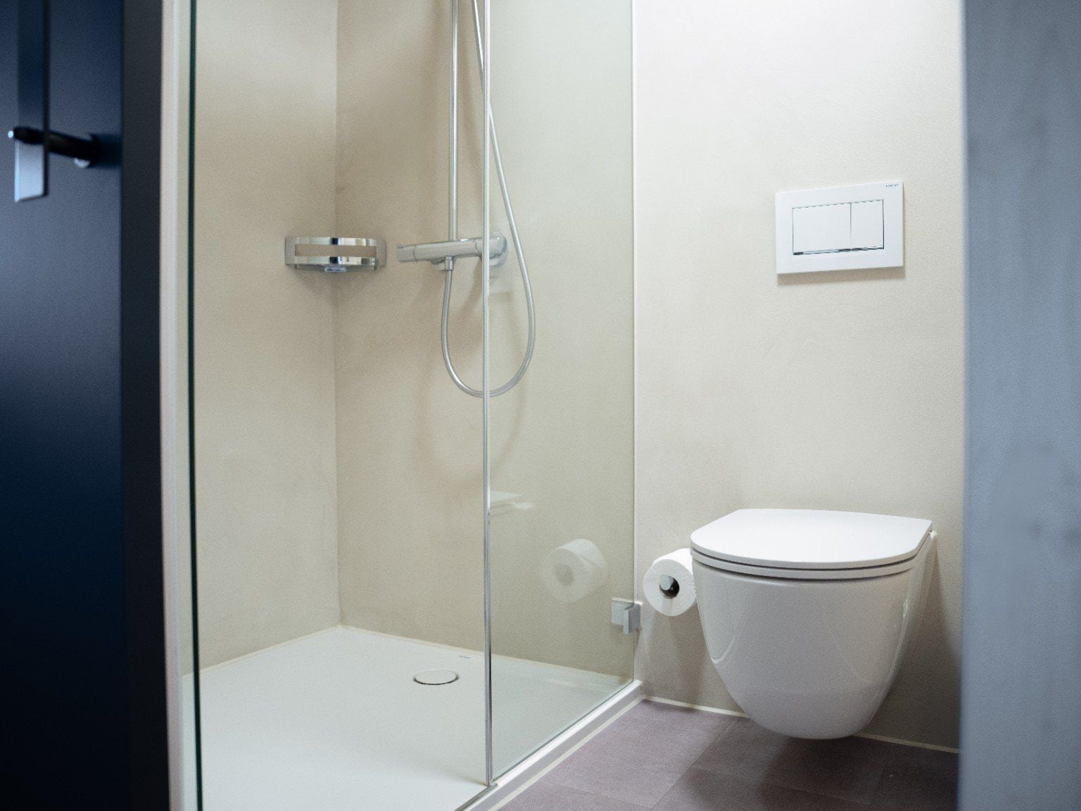 Ein Badezimmer mit einer Duschkabine, einer Toilette und einem an der Wand befestigten Lichtschalter.