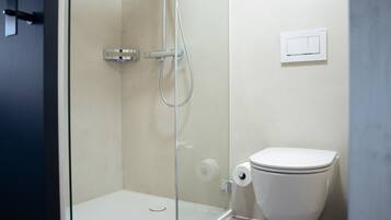 Ein Badezimmer mit einer Duschkabine, einer Toilette und einem an der Wand befestigten Lichtschalter.