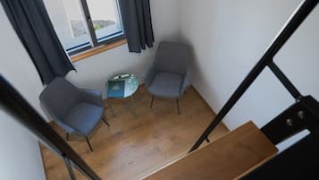 Ein Zimmer mit zwei Stühlen, einem kleinen Tisch und einem Fenster mit Vorhängen.