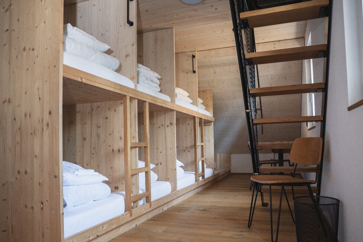 Una habitación con literas de madera, un escritorio y una silla.