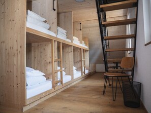 Una habitación con literas de madera, un escritorio y una silla.