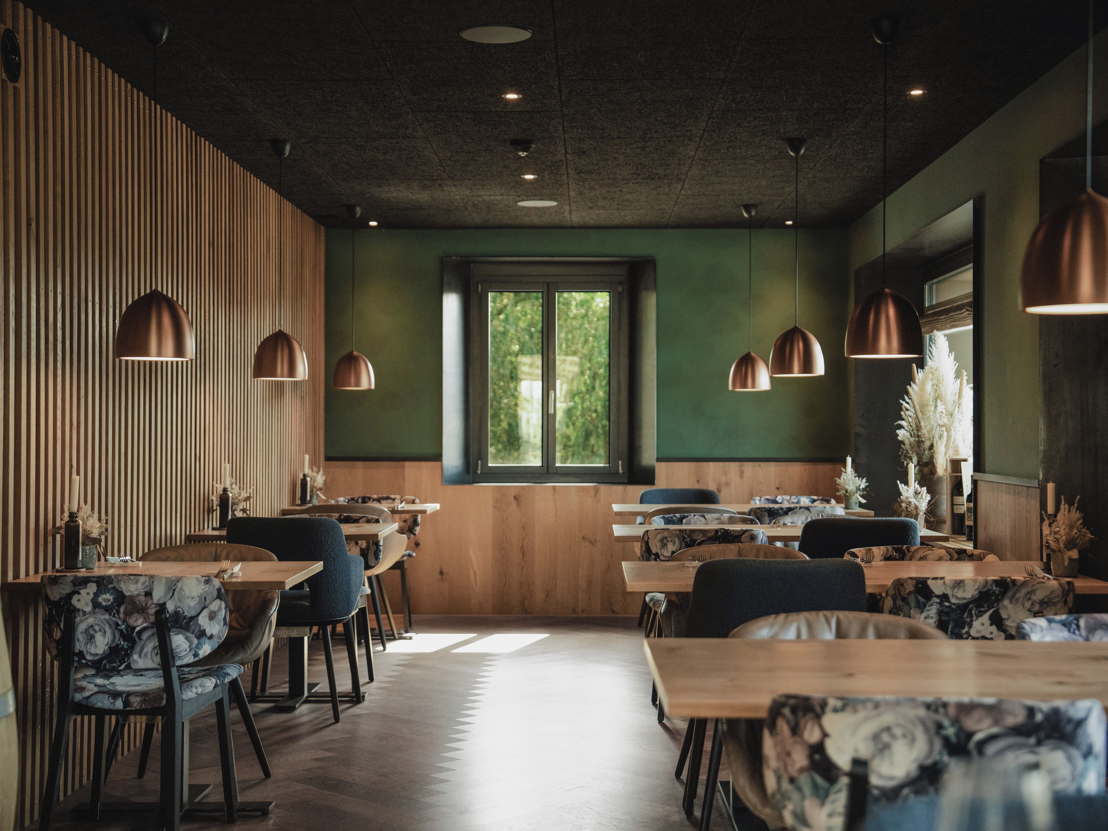 Un interior de restaurante con paredes de madera, paredes verdes y varias mesas de comedor con sillas.