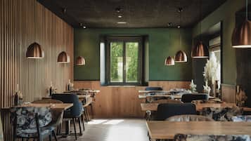 Un interior de restaurante con paredes de madera, paredes verdes y varias mesas de comedor con sillas.