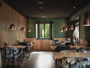 A restaurant interior with wooden panel walls, green walls, and multiple dining tables with chairs.