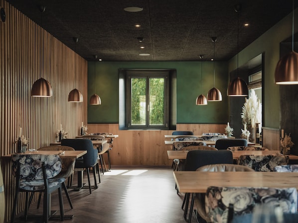 Un interior de restaurante con paredes de madera, paredes verdes y varias mesas de comedor con sillas.