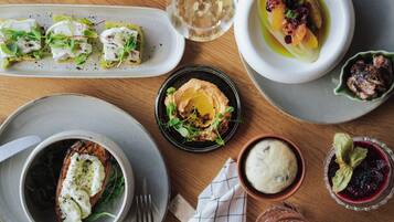 Variedad de platos sobre una mesa de madera, incluyendo un tazón de sopa, un plato con ensalada verde y un recipiente con huevo escalfado.