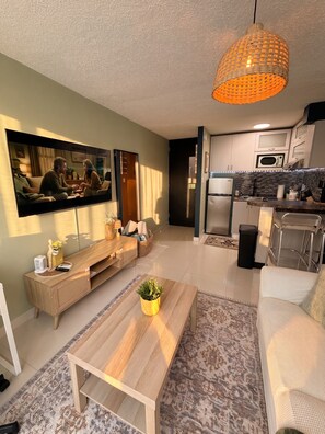 Een moderne woonkamer met een flatscreen televisie, een houten salontafel en een bank.