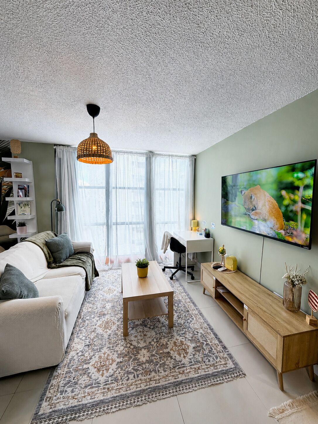 Ein modernes Wohnzimmer mit einer Couch, einem Couchtisch, einem Fernseher und einem gemusterten Teppich.