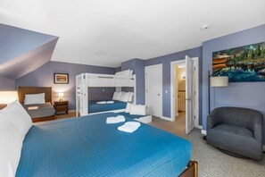 Een hotelkamer met een stapelbed, een bureau, een stoel en een schilderij aan de muur.