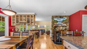 A spacious kitchen with wooden cabinets, a granite countertop, and a stone accent wall. - 5BR Home Quietside of MDI - Sleeps 23! [Headlands] (Tremont)