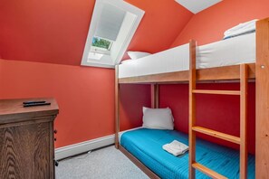 Ein Schlafraum mit Etagenbetten, Schreibtisch und Fenster.