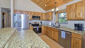 Una cucina moderna con piani di lavoro in granito, elettrodomestici in acciaio inossidabile, mobili in legno e un'ampia finestra che offre luce naturale.