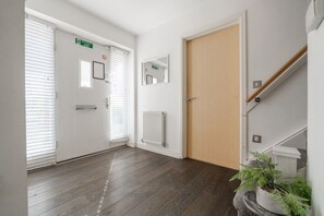Ein Flur mit Holzboden, weißen Wänden und einer Tür mit Notausgangsschild.