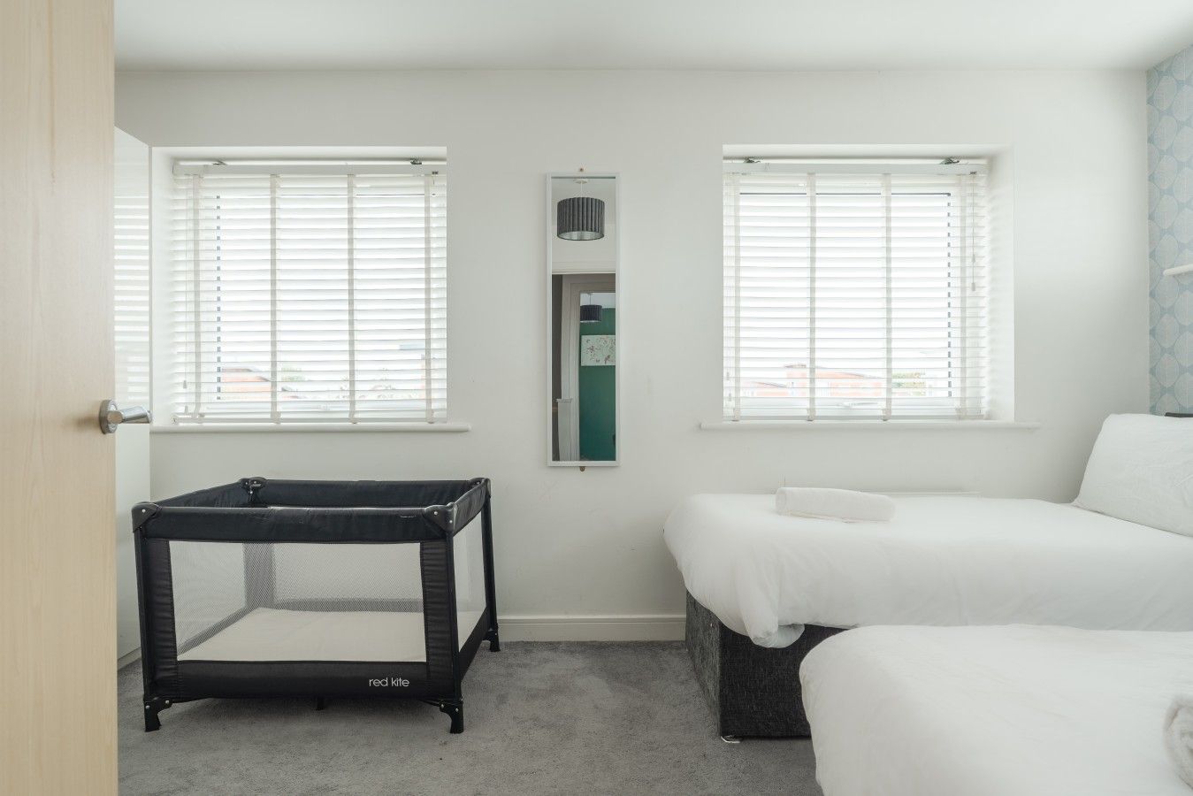 Un dormitorio con dos camas, una ventana, una puerta y una mesita.