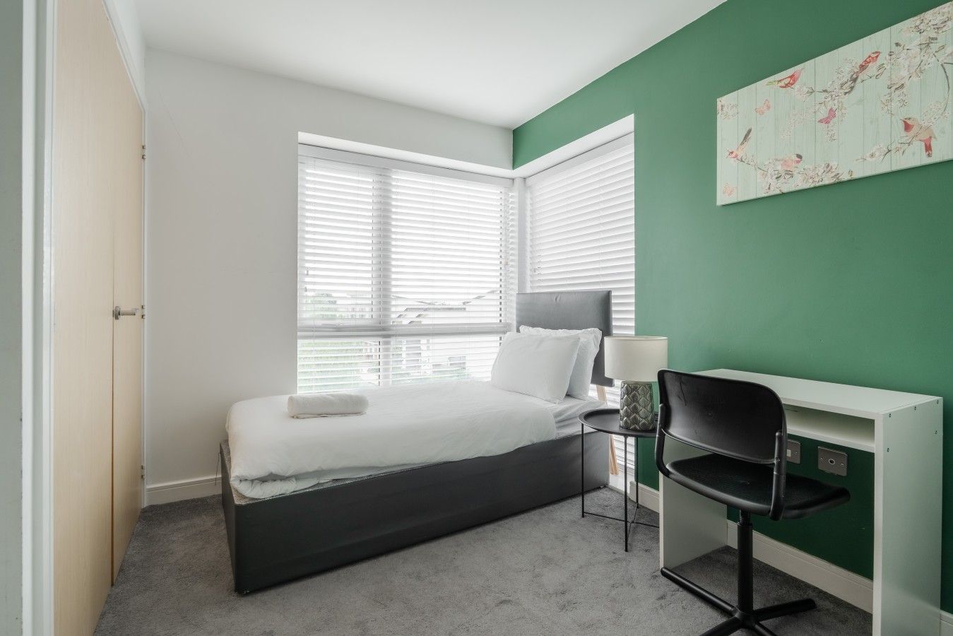 Quarto com cama, escrivaninha e cadeira.