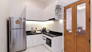 A compact kitchen with a stainless steel refrigerator, a built-in oven, and a microwave. - Spacious Heritage House Prime Location Family Stay (Bangkok)