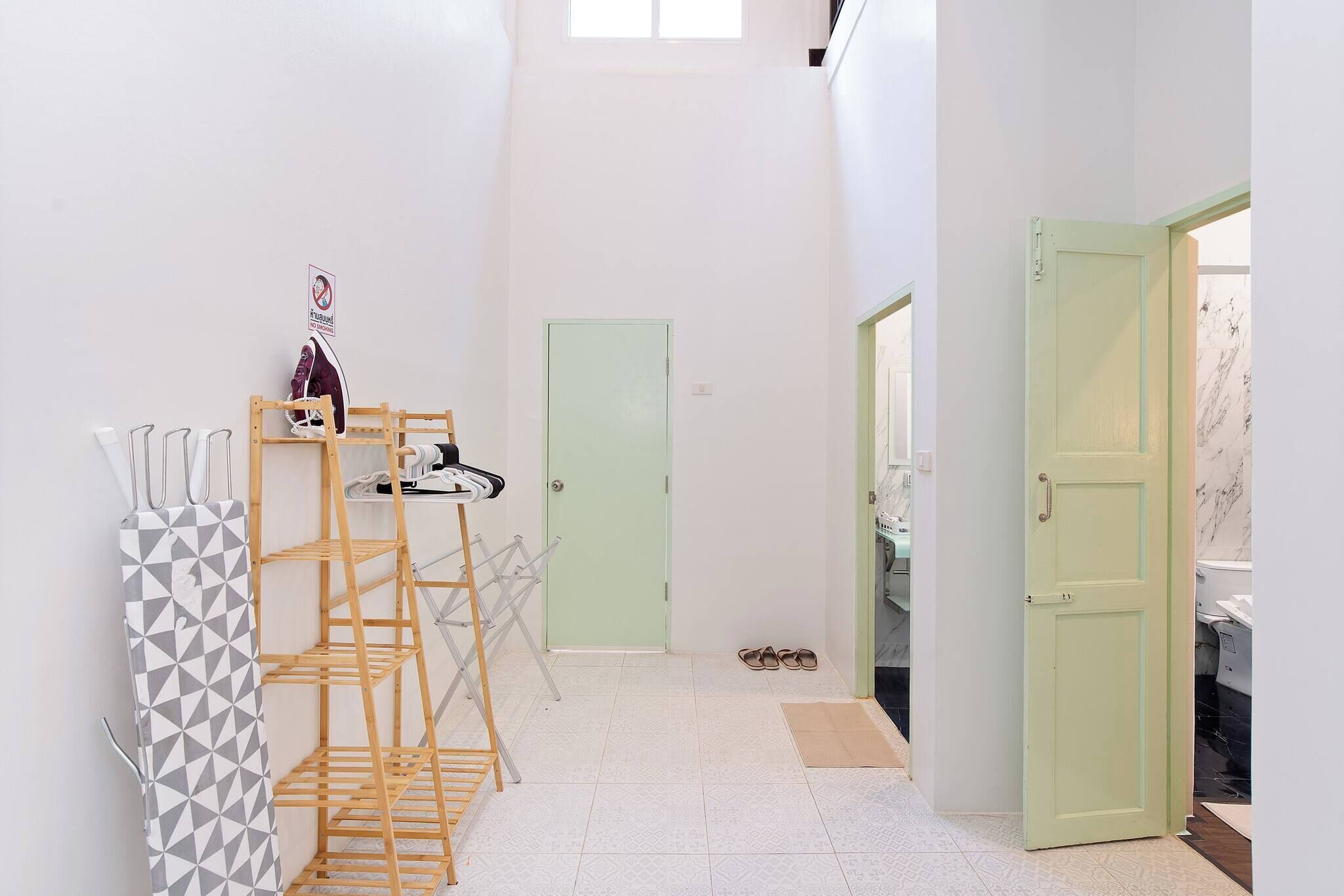 A hallway with a wooden rack, a door, and a view into a room with a washing machine.
