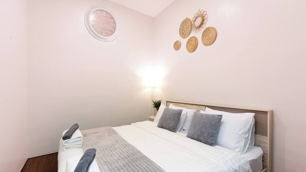 A neatly made bed with a white comforter, grey and white pillows, and a grey throw blanket. - Spacious Heritage House Prime Location Family Stay (Bangkok)
